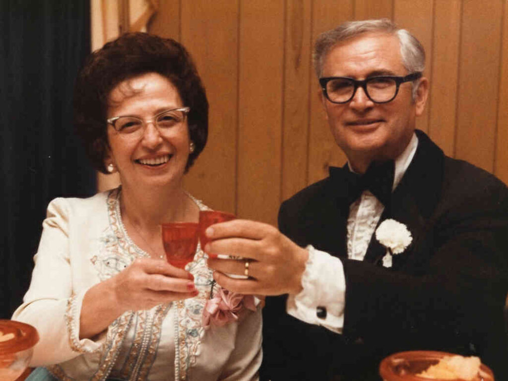 Domenic and his wife Margarette (Nana and Nonnu) smiling and raising a toast in formal attire, the inspiration for The Pasta Tempo.